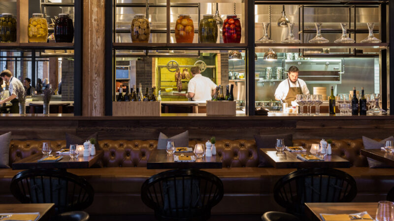 Neatly set tables overlooking the kitchen at Tullibee restaurant in Minneapolis