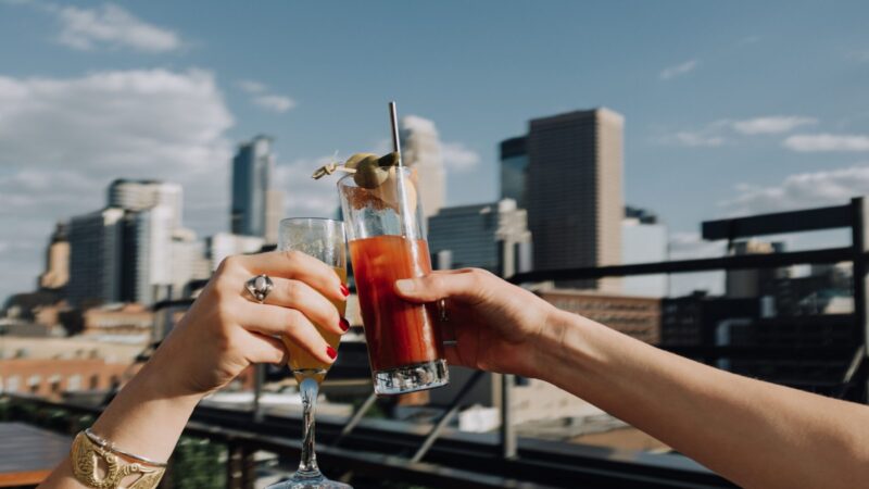 Two hands clinking cocktails on our rooftop downtown Minneapolis bar